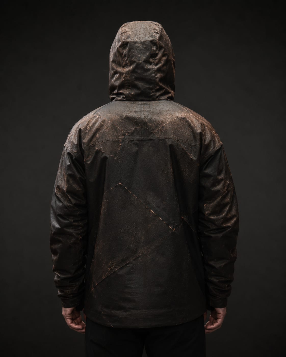 A hooded figure from behind, wearing a dark jacket veined with copper scars